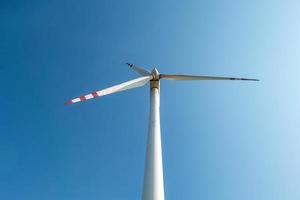 roterande blad av en väderkvarn propeller på blå himmel bakgrund. vindkraftsproduktion. ren grön energi. foto