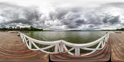 full sömlös sfärisk hdri panorama 360 graders vinkelvy på träbrygga för fartyg på enorm sjö i grå regnhimmel i ekvirektangulär projektion, vr ar innehåll. foto