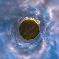 grön liten planet i blå himmel med sol och vackra moln. transformation av sfäriskt panorama 360 grader. sfärisk abstrakt flygfoto. utrymmets krökning. foto