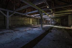 inuti mörk övergiven ruinerad trä förfallen hangar med ruttnande kolonner foto