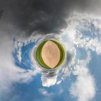 liten planetomvandling av sfäriskt panorama 360 grader. sfärisk abstrakt flygfoto i fältet i trevlig dag med fantastiska vackra moln. utrymmets krökning. foto