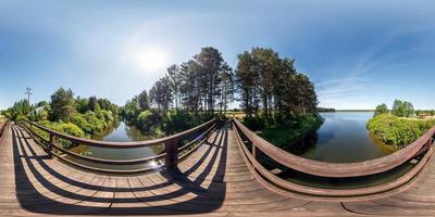 full sömlös panorama 360 x 180 vinkelvy på träbro över vattenkanalen mot bakgrund av en enorm sjö i solig sommardag i ekvirektangulär projektion, skybox vr virtual reality-innehåll foto