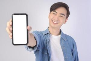 ung asiatisk man använder smartphone över vit bakgrund, teknik koncept. foto