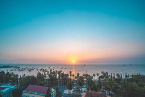 vung tau stadens flygfoto med vacker solnedgång och så många båtar. panoramautsikt över kustnära vung tau från ovan, med vågor, kustlinje, gator, kokospalmer och tao phung-berget i vietnam. foto