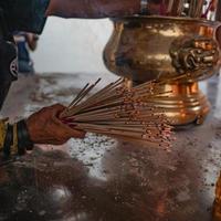 en massa brinnande josspinnar på folk hand i templet foto