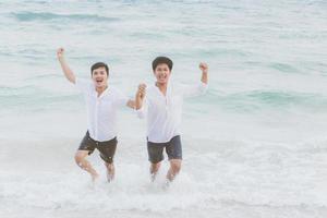 homosexuella porträtt ungt asiatiskt par springer med glada tillsammans på stranden på sommaren, asien gay turism för fritid och koppla av med lycka i semestern till sjöss, hbt juridiskt koncept. foto