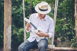 man spelar ukulele som är ny för floden - människor och musikinstrument livsstil i naturen koncept foto