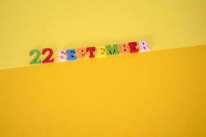 22 september på gul och pappersbakgrund med träbokstäver och siffror i olika färger. foto
