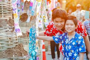 thailändsk familj deltar i gammal traditionell aktivitet i ett tempel under songkran-festivalen i chiang mai, norra thailand, mycket berömd händelse i thailand foto