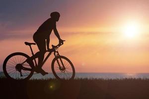 silhuetter av mountainbikes och cyklister på kvällen glatt. resor och fitness koncept. silhuett av cyklister som turnerar på kvällen cykelturnékoncept foto