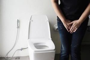 kvinna som håller handen nära toalettskålen - hälsoproblem koncept foto