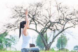 ung dam som gör yogaövningar i grönt fält utomhusområde som visar lugn fridfull i meditationssinnet - människor utövar yoga för meditation och träningskoncept foto