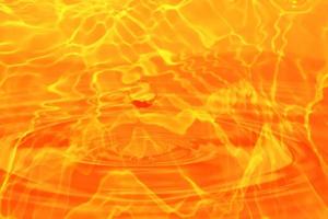 oskärpa suddig genomskinlig orange färgad klar lugn vattenyta textur med stänk och bubbla. trendiga abstrakt natur bakgrund. vattenvåg i solljus med kopia utrymme. orange vattendroppe färg foto