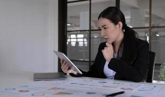 affärskvinna som använder en pekplatta för att visa sina e-postmeddelanden på sitt skrivbord på kontoret. foto