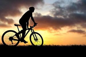 silhuetter av mountainbikes och cyklister på kvällen glatt. resor och fitness koncept. silhuett av cyklister som turnerar på kvällen cykelturnékoncept foto