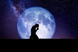en desperat och ensam man knäböjde och bad till gud. det finns en måne i bakgrunden på natten. desperata, hjärtskärande och ensamma koncept foto