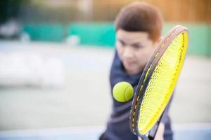 man håller racket på väg att slå en boll i tennisbanan - människor i tennisspel match koncept foto