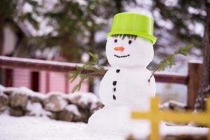 leende snögubbe med grön hatt foto