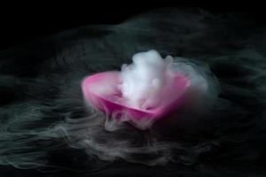 rök av torris med rosa hjärtformad kopp isolerad på svart bakgrund foto