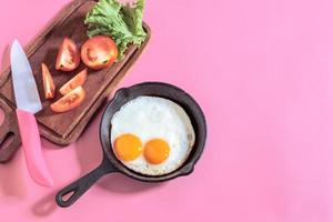 hälsosam frukost mat stekt ägg i stekpanna på rosa bord. foto