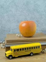 skolbussleksaken och äpplet på träbord för tillbaka till skolan eller utbildningskonceptet foto