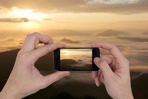 manliga händer som håller smartphone ta bild av bergslandskap. foto