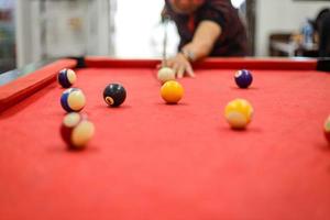 närbild av en mans hand som spelar biljard som förbereder sig för att skjuta den vita bollen till gul boll med en komplett uppsättning poolbollar foto