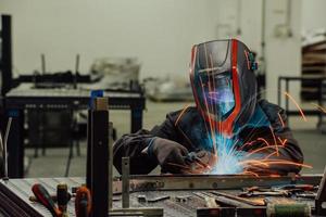 professionell tungindustrisvetsare som arbetar inne i fabriken, bär hjälm och börjar svetsa. selektiv fokusering foto