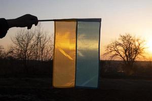gul blå flagga Ukraina i handen mot solnedgången himlen foto