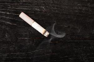cigarettfimp på golvet mot en mörk bakgrund, nikotinberoende foto