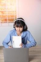en ung asiatisk tjej sitter hemma och studerar. foto