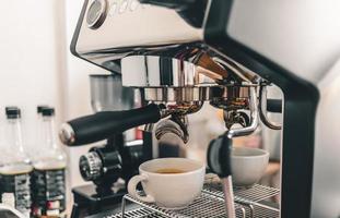 kaffeutvinning från den professionella barista kaffemaskinen. espresso upphällning från en kaffemaskin i en kopp kaffe på ett kafé. foto