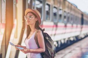 turist resor kvinna tittar på kartan medan du går på järnvägsstationen - gata ryggsäck resor koncept foto