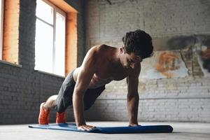 koncentrerad ung man gör push-up övningar i gymmet foto