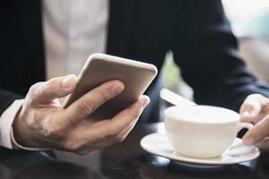 affärsman som använder mobiltelefon medan du dricker kaffe i kafé - modern livsstil affärsman i kafé koncept foto