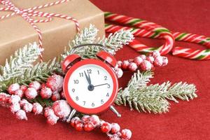 julsnögran, väckarklocka och presentförpackning på röd bakgrund. foto