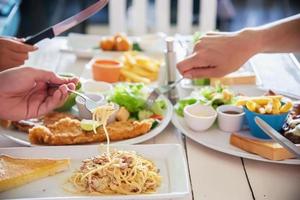 människor tycker om att äta spagetti och biff tillsammans i en stor måltidsuppsättning - familjen glad tid med matkoncept foto