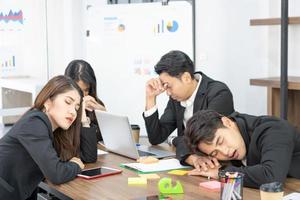 affärsteammedlemmar som sover på skrivbord och stolar. ett affärsteam är trötta efter ett långt möte. foto