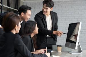 framgångsrikt företag multiage team står runt datorn för presentation av arbete. grupp av affärsmän i ett möte på kontoret, arbetar på datorn foto