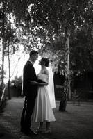 ungt par brudgummen i en svart kostym och bruden i en vit kort klänning foto