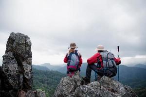 unga turist par tittar på spektakulära bergslandskap i höga berg. man och kvinna vandrare på toppen rock. ett par förälskade resenärer. människor hälsar gryningen. älskare reser. kopieringsutrymme foto