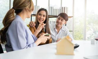 fastighetsmäklaren ger nyckeln till klienten efter att ha undertecknat bostadslånedokumentet med fastighetsmäklaren eller advokaten. begreppet försäkring eller lån fastigheter, köpa ett hus. foto