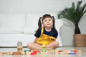 söt asiatisk liten flicka som leker med färgglada leksaksblock, barn leker med pedagogiska leksaker på dagis eller dagis. kreativ lek av barnutvecklingskoncept, småbarnsbarn i barnkammare. foto