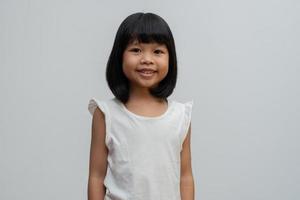 porträtt av glad och rolig asiatisk barnflicka på vit bakgrund, ett barn som tittar på kameran. förskolebarn drömmer fylla med energi känner sig frisk och bra koncept foto