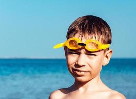 pojke med vått hår bär glasögon nära havet efter dykning foto