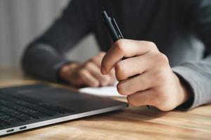 affärsman håller pennan med vänster hand arbetar med laptop på kontoret. foto