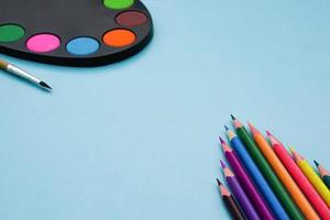 konstpalett med färg, pensel och färgpennor på blå bakgrund. foto