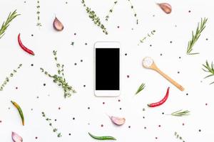 smartphone med gröna örter och kryddor runt foto