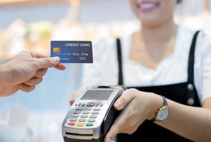 kund i café betalar via kreditkort till butiksbiträde foto