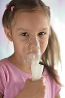 härlig liten flicka med inhalator foto